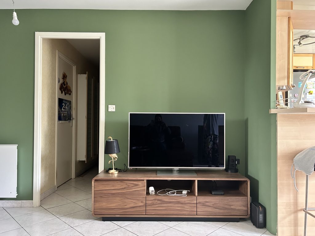 Meuble TV en noyer fumé et mur vert dans un salon Art Déco rénové