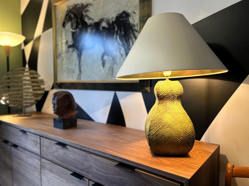 Détail du buffet en noyer sur-mesure et sculpture artistique avec mur graphique noir et blanc en arrière-plan.